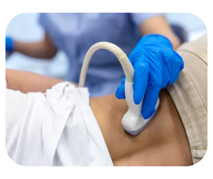 Hand in blauem Einweghandschuh hält Ultraschallkopf auf den unteren Rücken einer liegenden Person. 