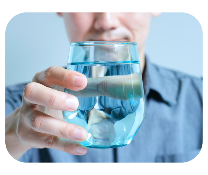 Ein Mann hält ein Glas mit Wasser. 