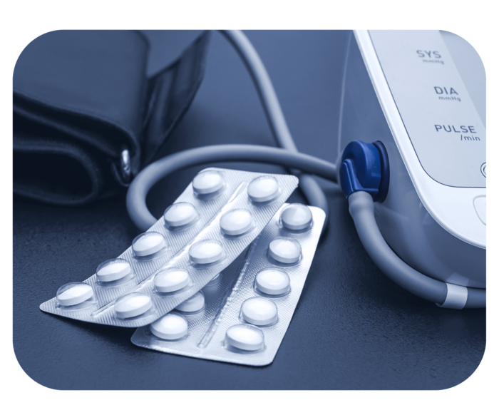 Zwei Medikamentenblister liegen neben einem Blutdruckmessgerät.