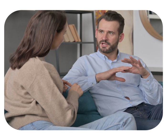 Ein Mann und eine Frau, die sich auf einem Sofa sitzend unterhalten.
