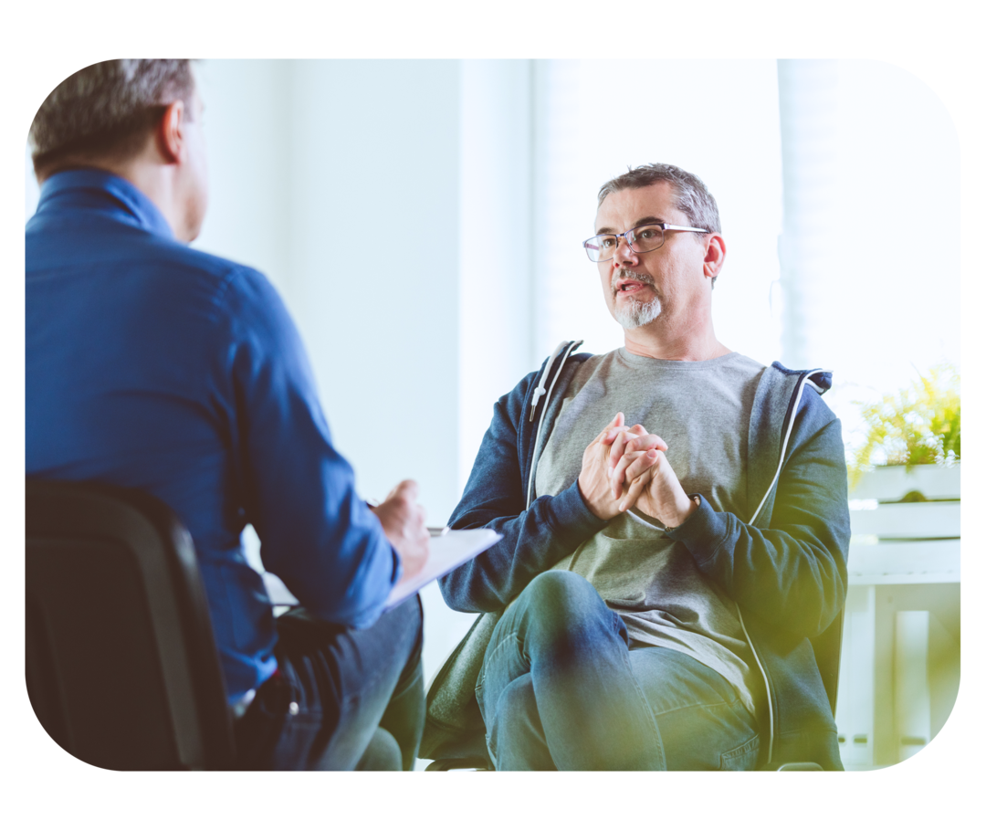 Nierenerkrankungen: Psychologische Hilfe  Mann mit grauen Haaren und Bart sitzt einem Mann mit Klemmbrett gegenüber.