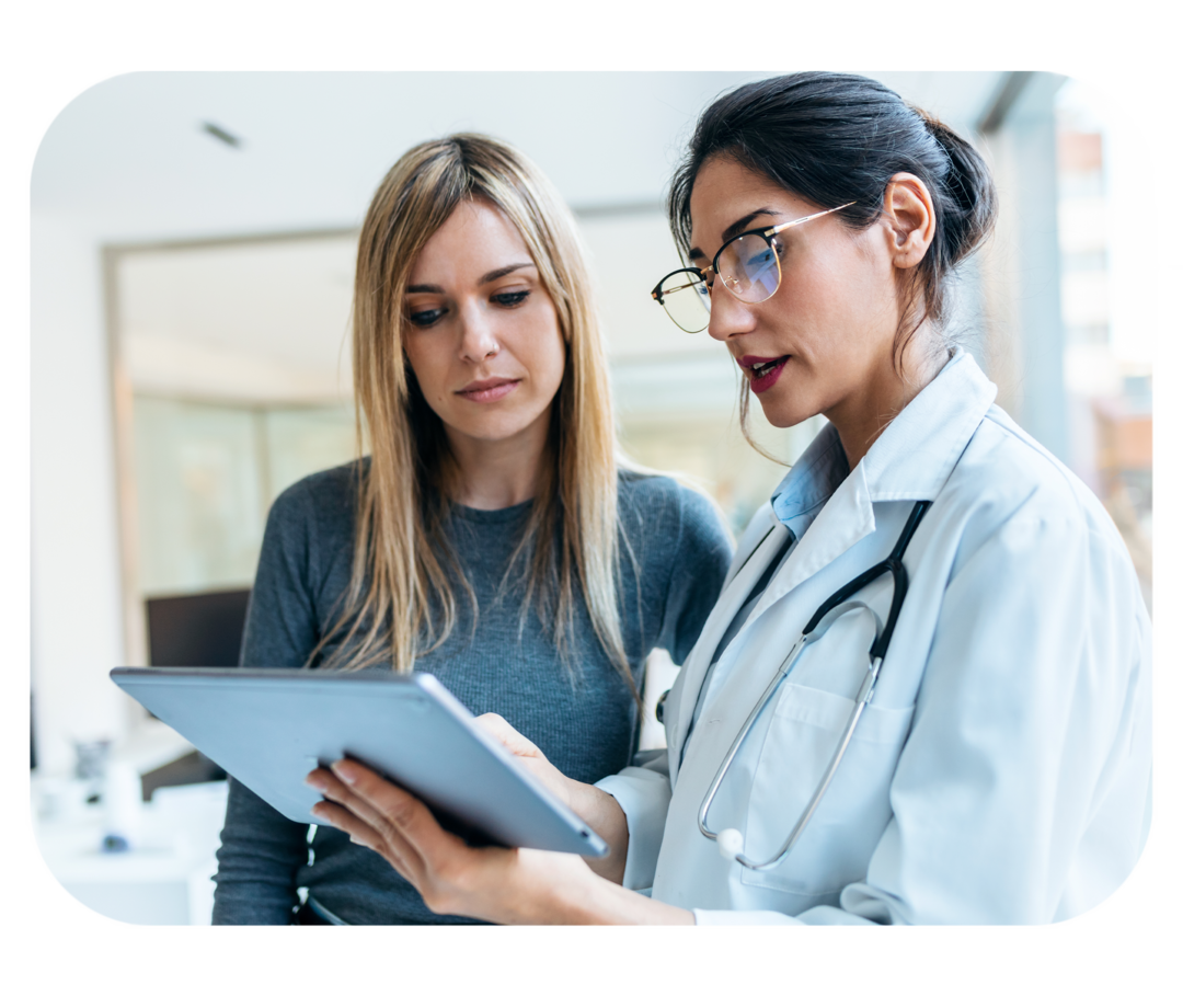 Frau in weißem Kittel im Gespräch mit einer Frau, die neben ihr steht.