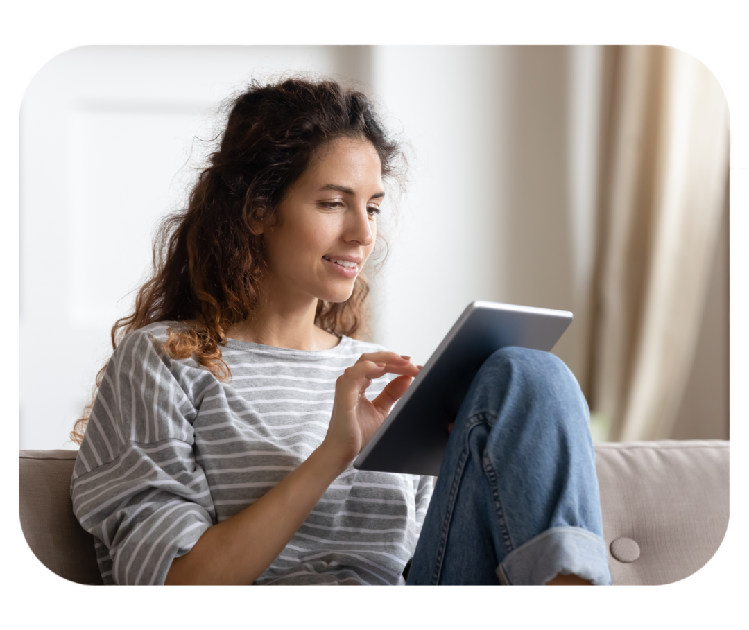 Junge Frau schaut auf ein Tablet, das sie in ihren Händen hält. 