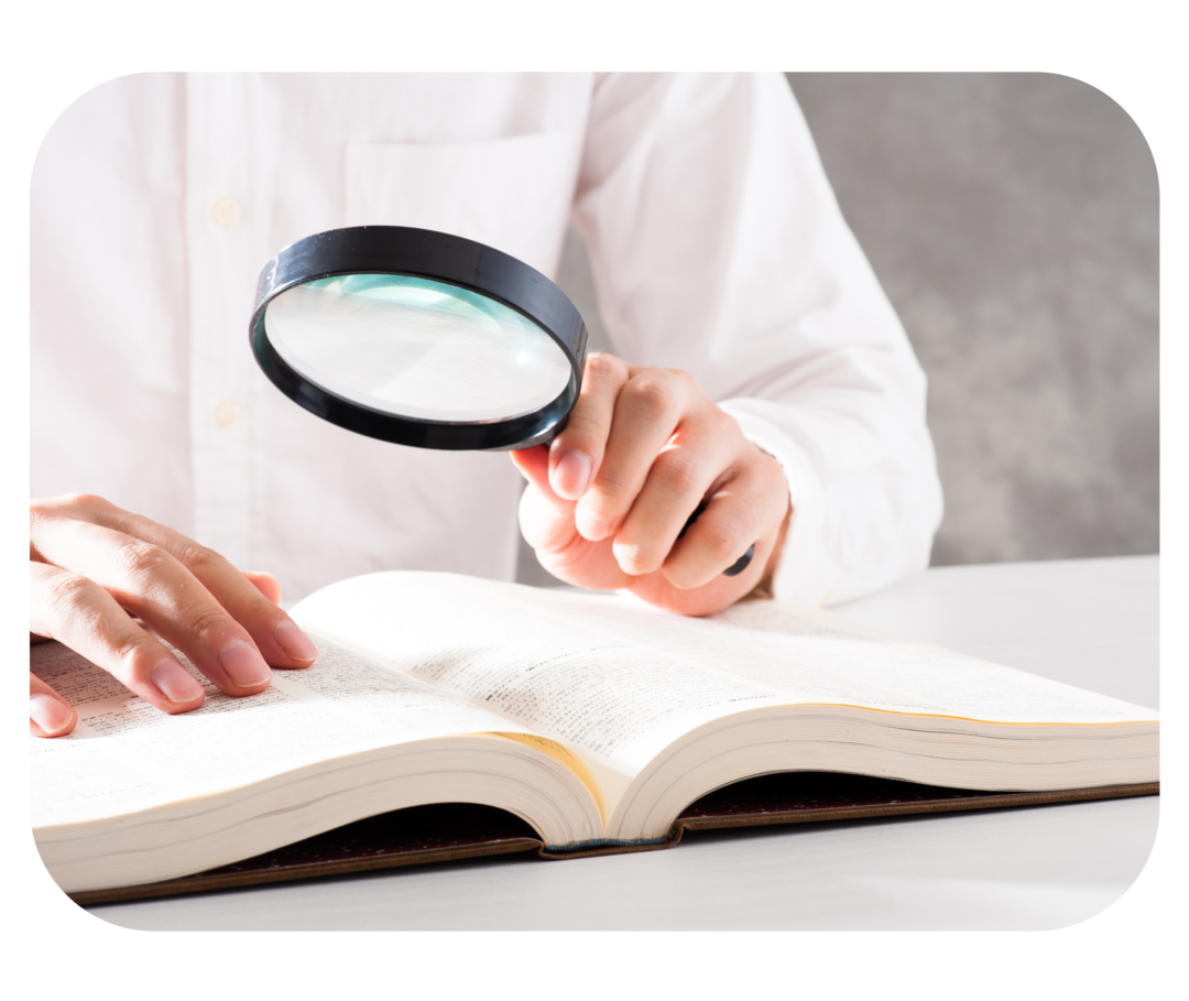 Oberkörper einer Person, die eine Lupe über ein Buch hält.