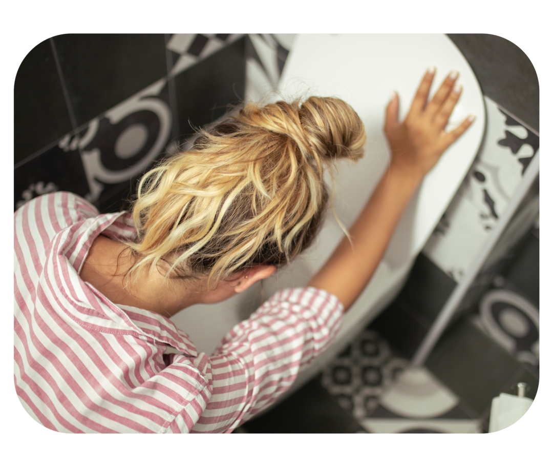 Eine Frau, die mit dem Kopf über eine Toilette gebeugt ist.