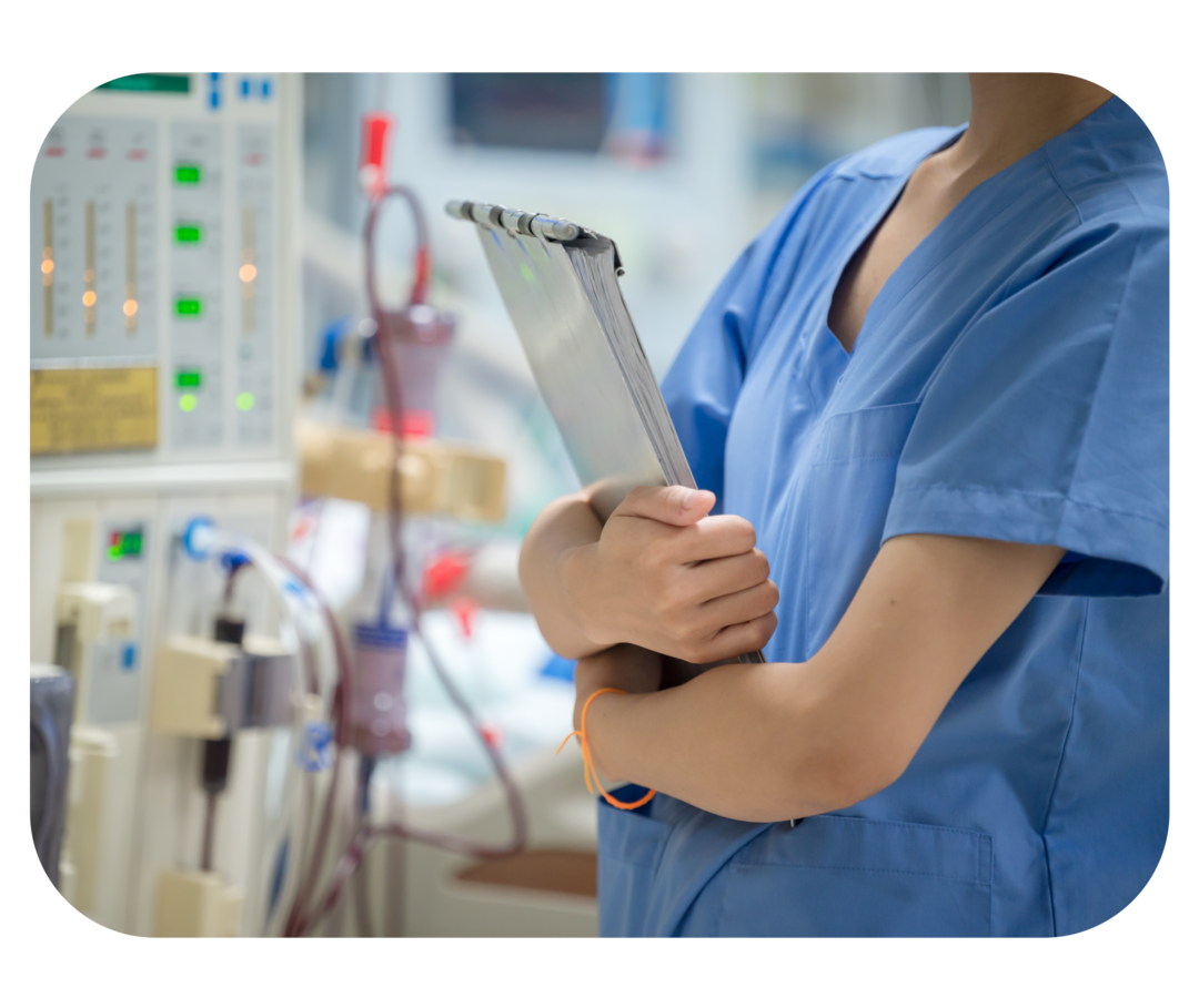 Person in blauem Kasack steht vor einer Hämodialyse-Maschine.