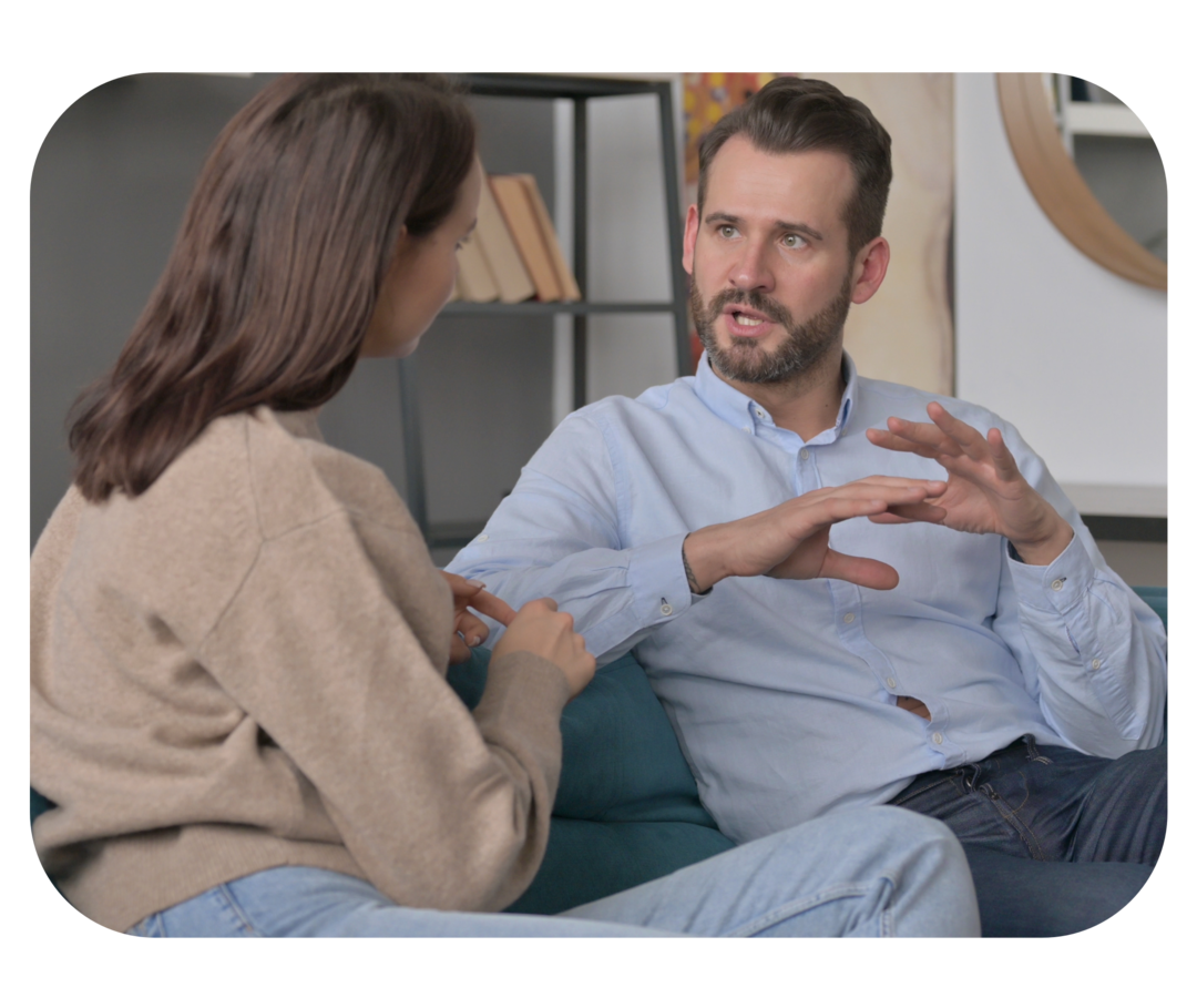 Ein Mann und eine Frau, die sich auf einem Sofa sitzend unterhalten.